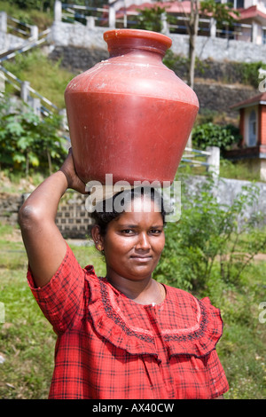 Dame transportant un grand récipient d'eau en plastique sur la tête, d'un puits, Western Ghats, Kerala, Inde Banque D'Images