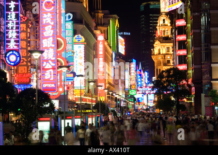 La Chine, Shanghai. Enseignes au néon et les piétons à Nanjing DongLu Road Shopping Paradise. Banque D'Images