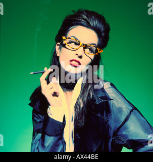 Jeune femme Cool cigarette portant des lunettes et à l'écart Banque D'Images