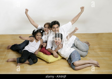 Portrait of a family sitting on floor and cheering Banque D'Images