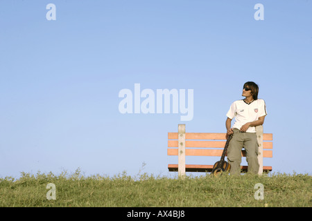 Jeune homme appuyé contre un banc de parc Banque D'Images
