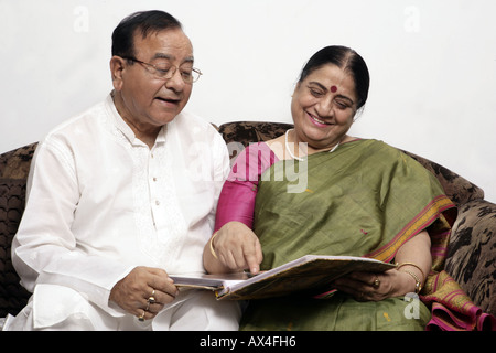 Senior couple regardant photo album et smiling Banque D'Images