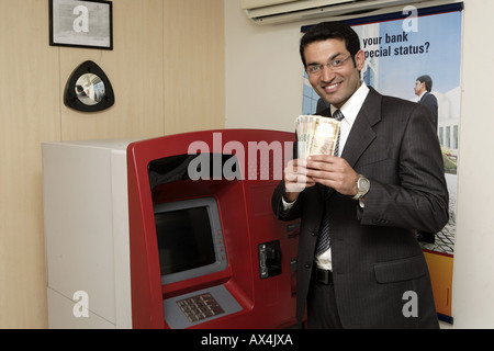 Portrait d'un homme d'affaires à l'aide de la banque ATM machine et smiling Banque D'Images