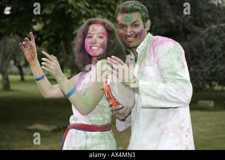 Portrait d'un couple playing holi et danser dans un parc Banque D'Images