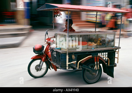 Un homme conduit sa motorisé, fruits mobile-distributeur, wc séparés à travers les rues de Ko Samui en Thaïlande. Banque D'Images