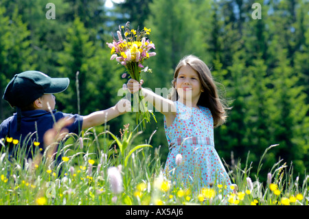 Petit garçon et fille avec bouquet de fleurs en été meadow Banque D'Images