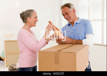 Mature couple holding champagne bouteille, smiling Banque D'Images