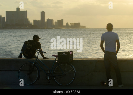 Deux hommes et un vélo à la Malecón, coucher de soleil, La Havane, Cuba Banque D'Images