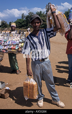 Jeune homme travaillant comme camelots vend du pain à une station de bus, Moshi, Tanzanie Banque D'Images