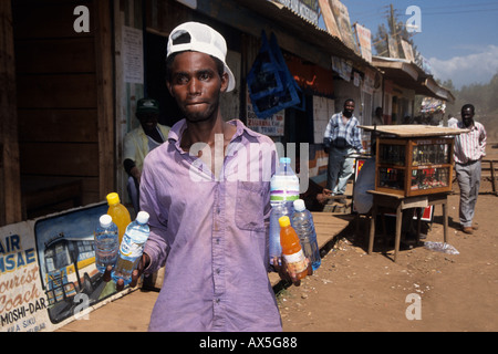 Jeune homme travaillant comme camelots vendant des rafraîchissements à une station de bus, Moshi, Tanzanie Banque D'Images