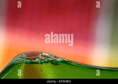 Détail d'une lessive liquide avec des bulles, à l'arrière un tissu coloré Banque D'Images