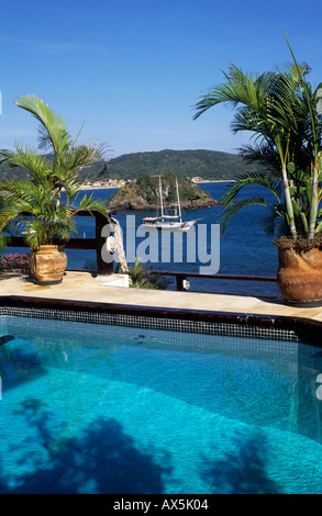 Buzios, Rio de Janeiro, Brésil. La piscine de l'hôtel Byblios avec la mer et un yacht privé au-delà. Banque D'Images