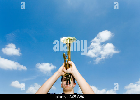 Jeune homme jouant de la trompette, low angle view Banque D'Images