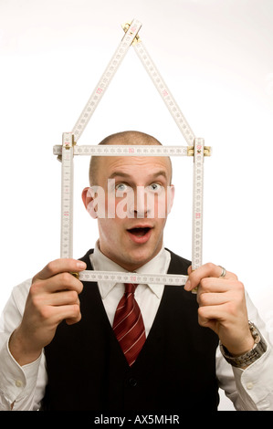 Man dressed in suit holding yardstick façonné dans une maison Banque D'Images