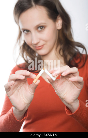 Jeune femme briser une cigarette dans la moitié Banque D'Images
