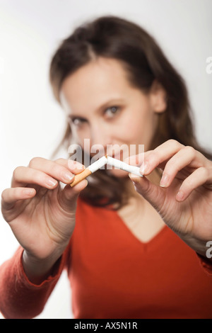 Jeune femme briser une cigarette dans la moitié Banque D'Images