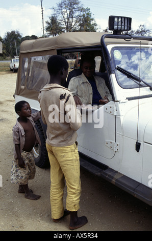 Mikumi, Tanzanie. Les enfants de la région de vendre des cacahuètes pour touriste dans une jeep à quatre roues motrices. Banque D'Images