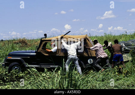 Chipundu, Zambie. Jeep à quatre roues motrices et d'une remorque ayant besoin d'une poussée d'échapper à la boue 'cross country' dans un marais. Banque D'Images