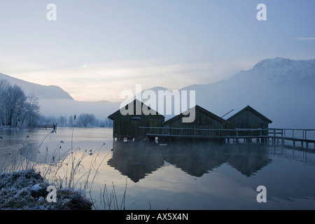 Les hangars à bateaux, gel-couverts de roseaux sur la rive du lac Kochelsee (Kochel) enshrouded dans la brume, pré-Alpes bavaroises, Upper Bavari Banque D'Images