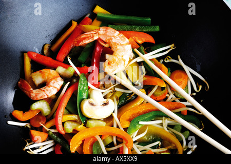 Les légumes et les crevettes cuites au wok avec des bâtons de broyage Banque D'Images