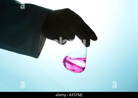 Chemist holding UNE FIOLE JAUGEE de liquide vers l'appareil photo Banque D'Images