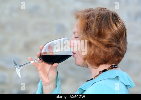 Côté sur les jeunes aux cheveux rouge Dame de boire un verre de vin rouge Banque D'Images