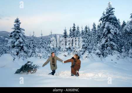 Couple en train de marcher dans la neige, faisant de l'arbre de Noël Banque D'Images