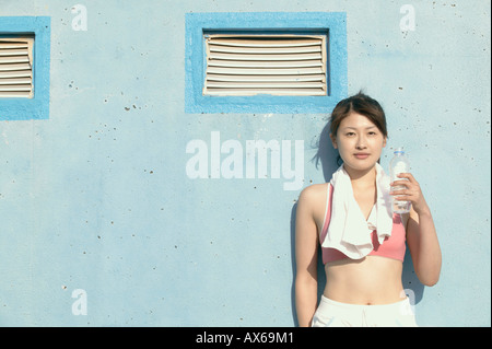 Une jeune femme tient la bouteille de l'eau comme elle regarde l'appareil photo Banque D'Images