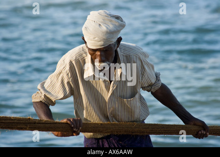 Vieil homme tirant dans les filets de pêche sur la plage de Varkala en Inde Banque D'Images