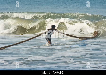 L'homme à l'océan tirant dans les filets de pêche sur la plage de Varkala en Inde Banque D'Images