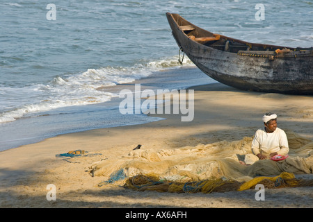 Fisherman Mending des filets sur la plage de Varkala en Inde Banque D'Images