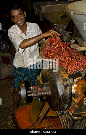 Jeune homme sec de meulage Red chili en poudre à Alleppey, Inde Banque D'Images