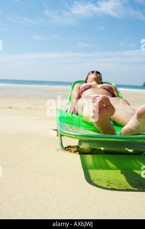 Femme en train de bronzer sur une chaise de plage Banque D'Images
