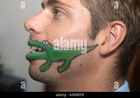 Caricature d'un crocodile vert peint sur le visage d'un jeune homme de race blanche Banque D'Images