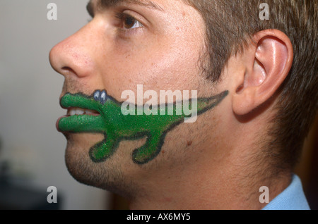 Caricature d'un crocodile vert peint sur le visage d'un jeune homme de race blanche Banque D'Images