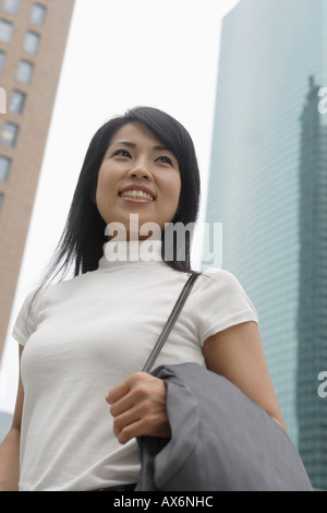 Une femme souriante avec des gratte-ciel à l'arrière-plan Banque D'Images