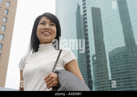 Une femme souriante avec des gratte-ciel à l'arrière-plan Banque D'Images