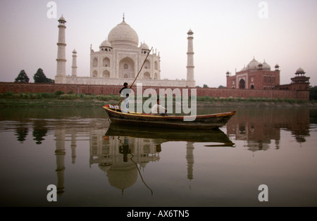 Un homme traverse une rivière en bateau derrière le Taj Mahal Banque D'Images