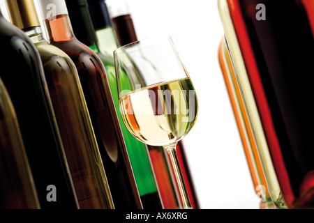 Verre de vin blanc entre les bouteilles de vin, close-up Banque D'Images