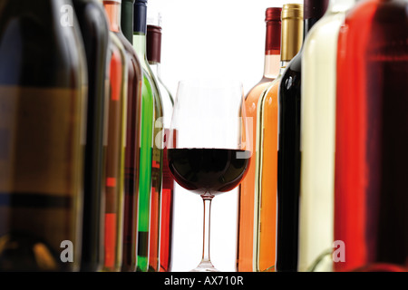 Verre de vin rouge entre les bouteilles de vin, close-up Banque D'Images