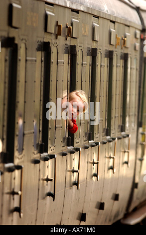 Sur le chemin de fer Bluebell dans East Sussex, un enfant regarde par la fenêtre pendant que le train à vapeur sort de la gare de Sheffield Park. Banque D'Images