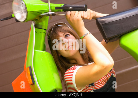 Jeune femme bricoler avec un scooter Banque D'Images
