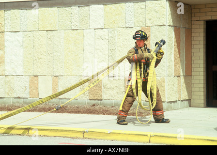 Un pompier est maintenant le tuyau d'incendie sur son épaule prêt à entrer dans un bâtiment et d'éteindre l'incendie Banque D'Images