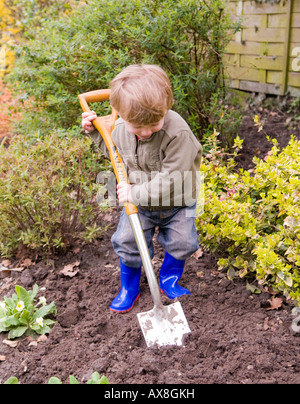 garçon de deux ans creusant dans le jardin. jouer avec la terre Banque D'Images