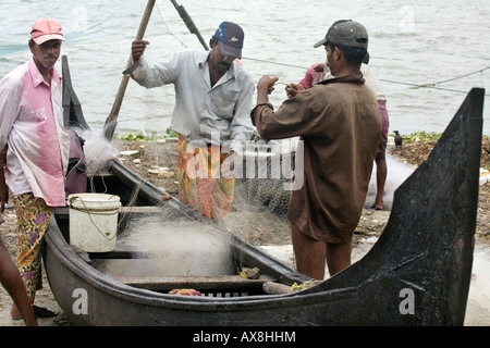 Les pêcheurs Keralite filets de vérification avant d'aller pêcher dans des pirogues locales valloms Beach Fort kochi Cochin Kerala Inde du Sud Banque D'Images