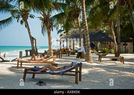 Les femmes se détendre et s'soleil sous les palmiers dans la Villa Beach Resort, sur la côte est de Zanzibar, Tanzanie Banque D'Images