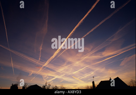 Des conditions météorologiques inhabituelles provoquant de nombreuses traînées de condensation des avions à se former dans l'aube ciel. Banque D'Images