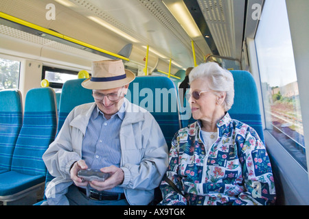 Un couple de personnes âgées dans un train en Angleterre la vérification les photos sur leur appareil photo numérique Banque D'Images