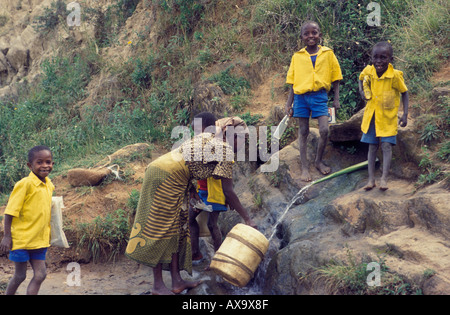 Femme à aller chercher de l'eau d'une source dans la falaise, en Tanzanie Banque D'Images