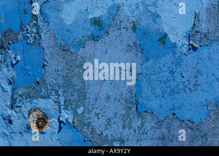 La peinture bleue pelée révèle des couches de vieillissement et de vieillissement, mettant en valeur les effets du temps sur une surface texturée. Banque D'Images